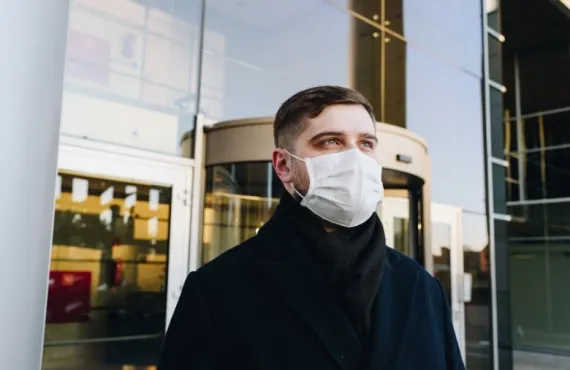 A man wearing a mask outside a building