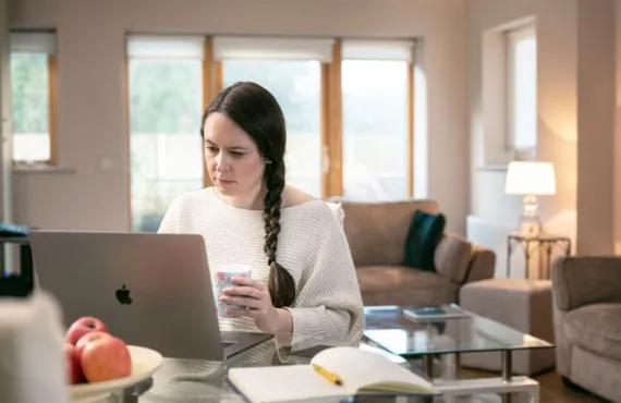 A woman working on her laptop at her kitchen table