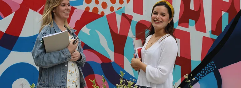 Two students standing in front of a Griffith College graffiti wall Two students standing in front of a Griffith College graffiti wall