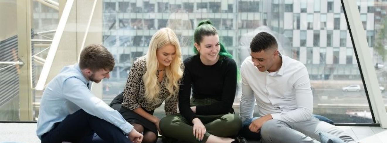 Apply now for the Central Bank of Ireland scholarship programme Four students sitting together on the floor working on a project