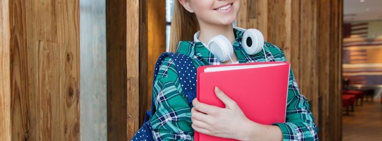 Griffith College learn and earn offers school leavers the chance to continue their education while starting their careers. A young woman standing in the hallway, holding school books and smiling at the camera