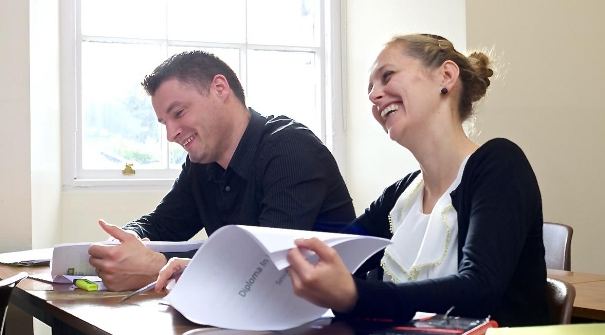 Mature female and male student laughing in class Mature female and male student laughing in class